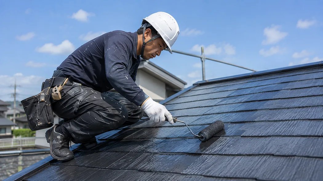 職人が住宅の屋根を塗装している様子
